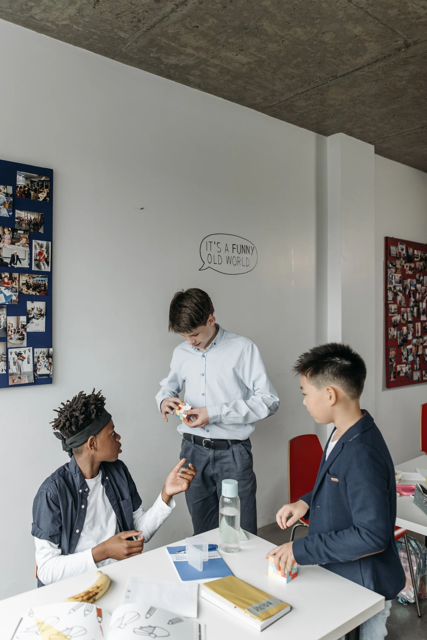 Three students work together around puzzle cubes and notebooks in a classroom.