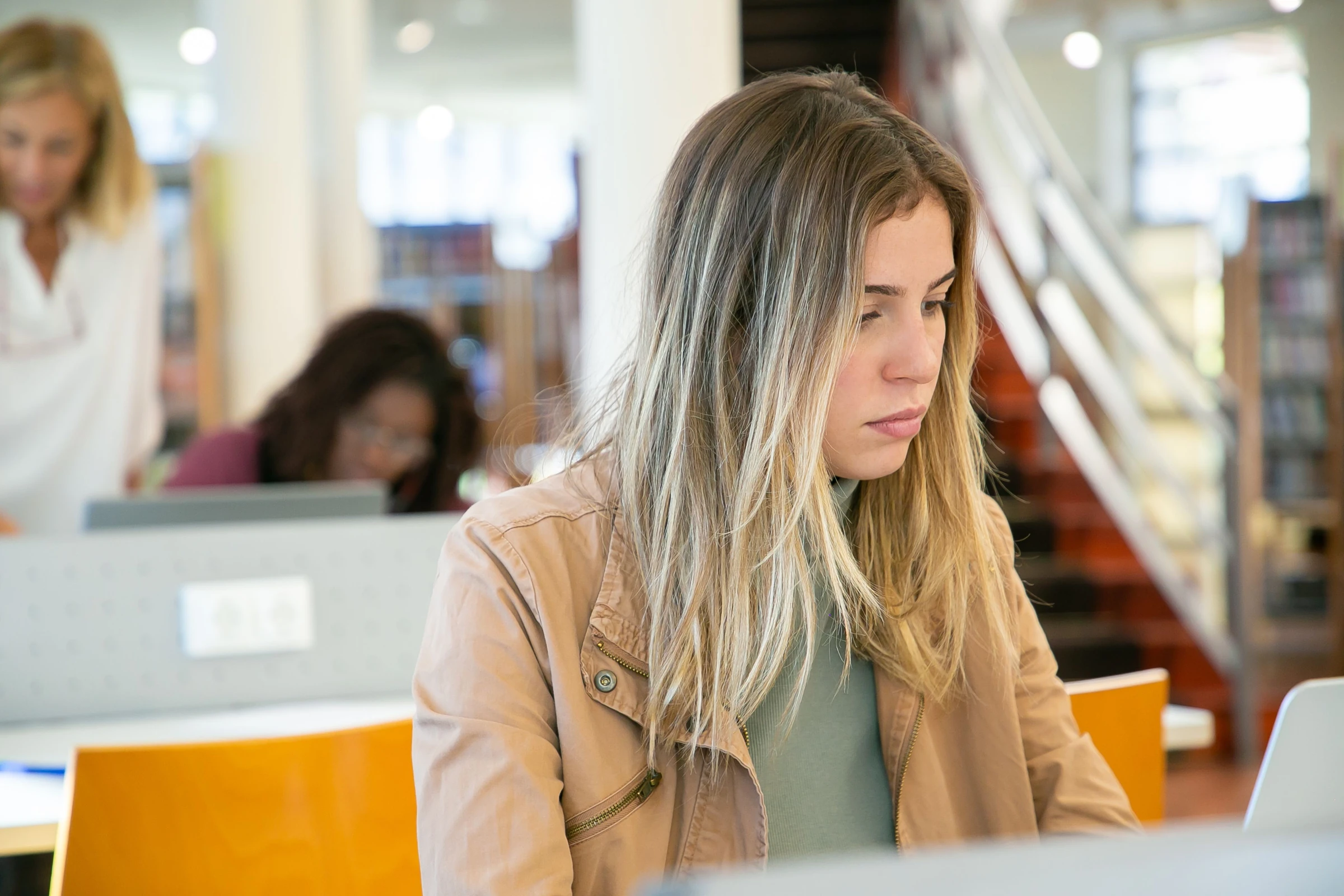A student concentrates on a laptop in a library.